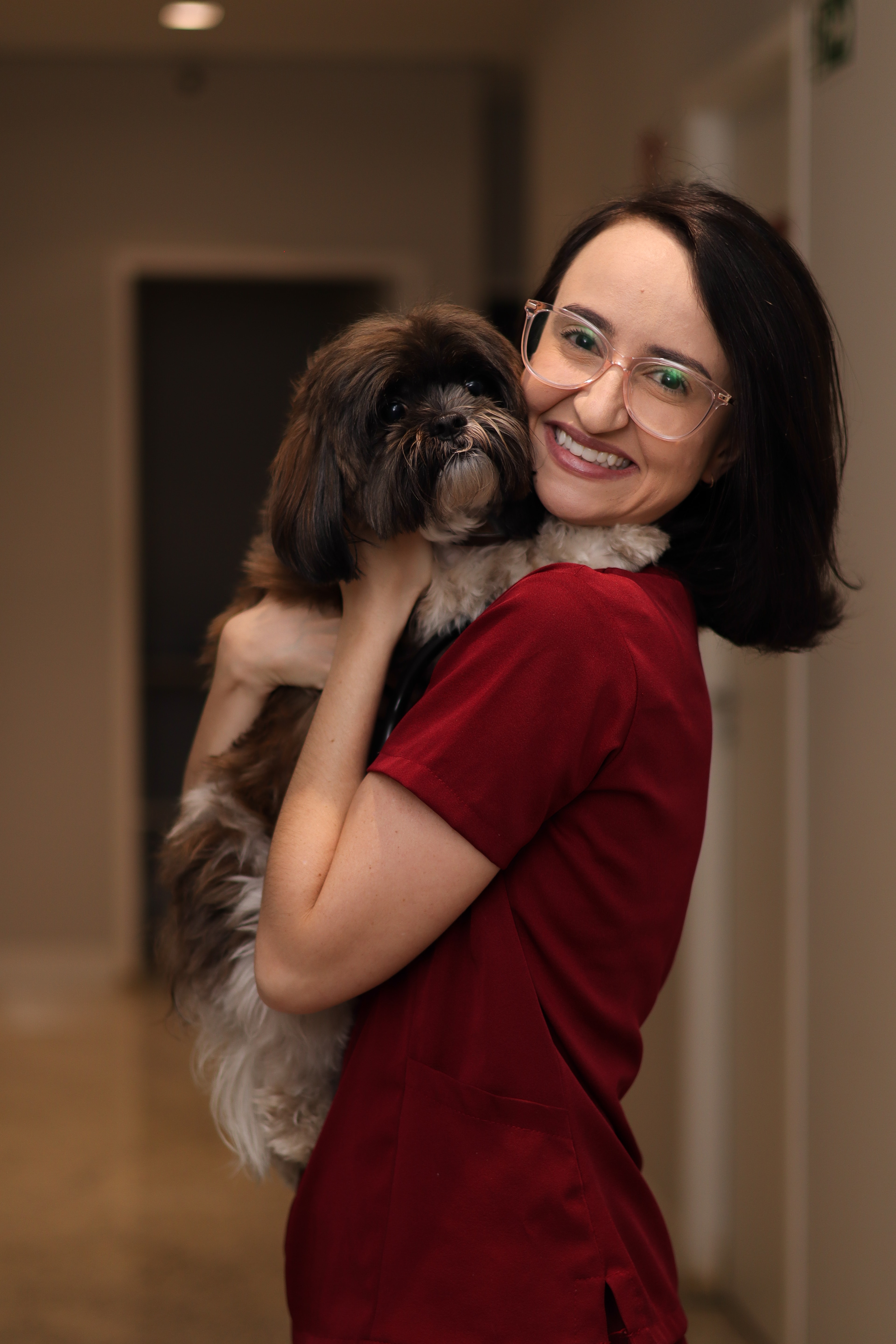 Vanessa sorrindo com um cão nos braços no consultório